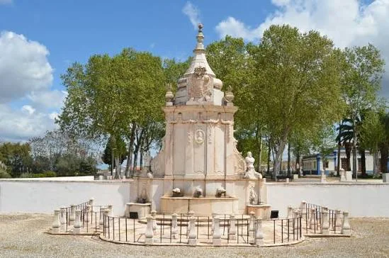 Baroque marble fountain, the Fonte das Bicas, among trees in Borba
