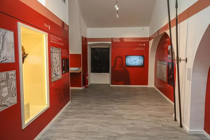 Red-walled exhibition hall with display panels at the Restoration War Interpretation Centre in Borba