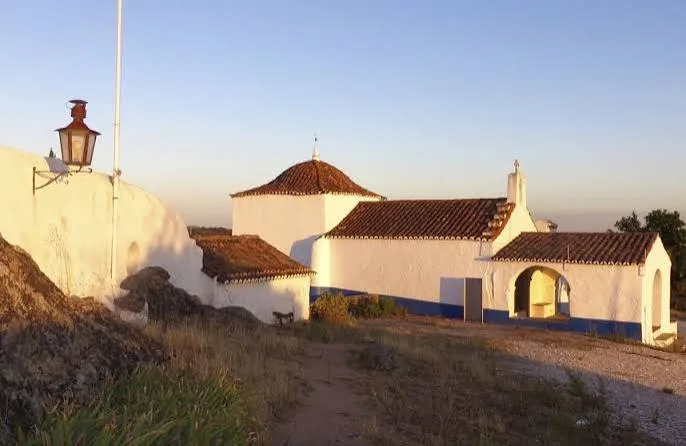 Whitewashed chapel with terracotta roofs in warm evening light, Borba