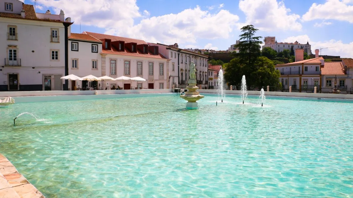 Fountain pool in a town square in Estremoz, with a castle on the hill behind