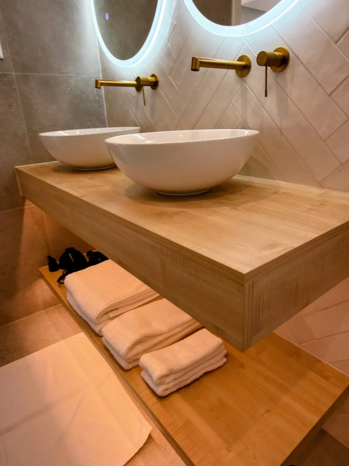 Two vessel basins on a wooden vanity with brass taps