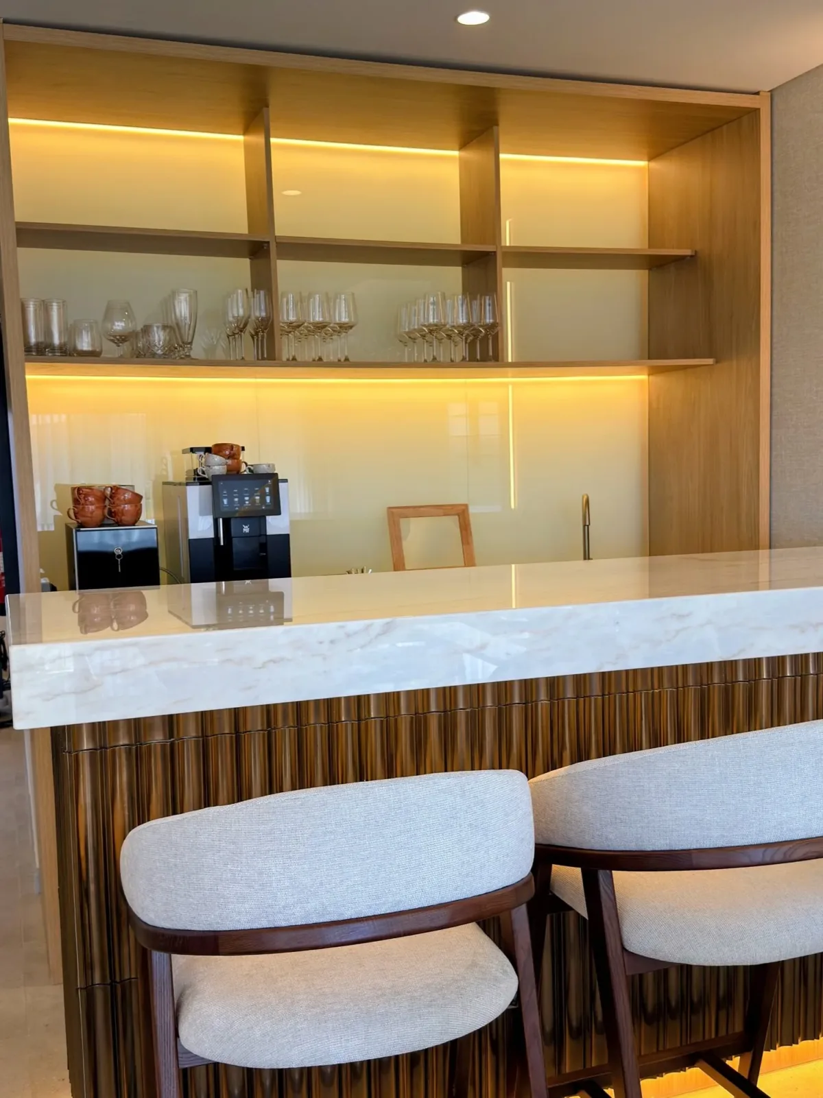Shelves with glasses and a coffee machine above the marble counter