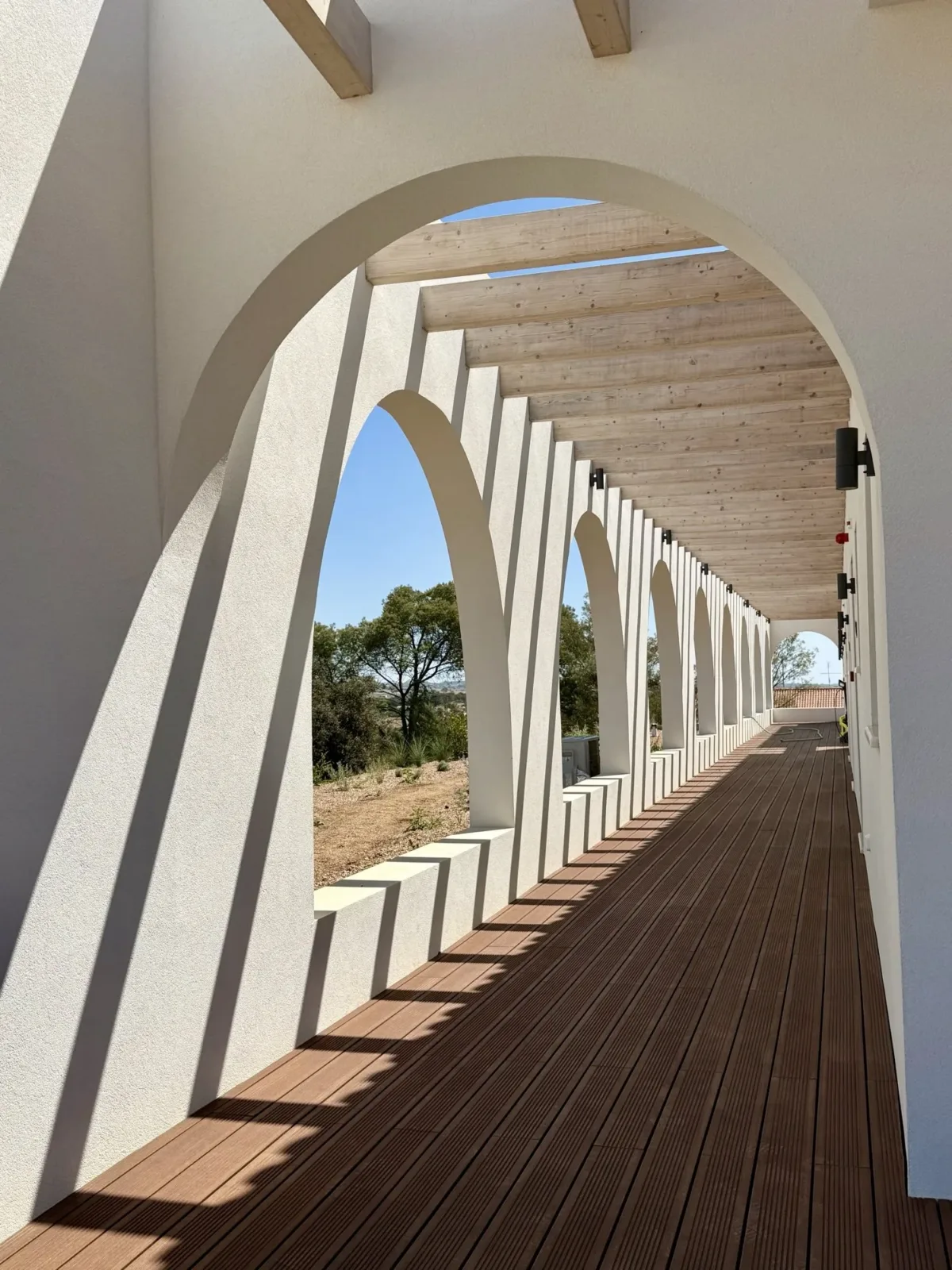Corredor branco de arcos com um deck de madeira