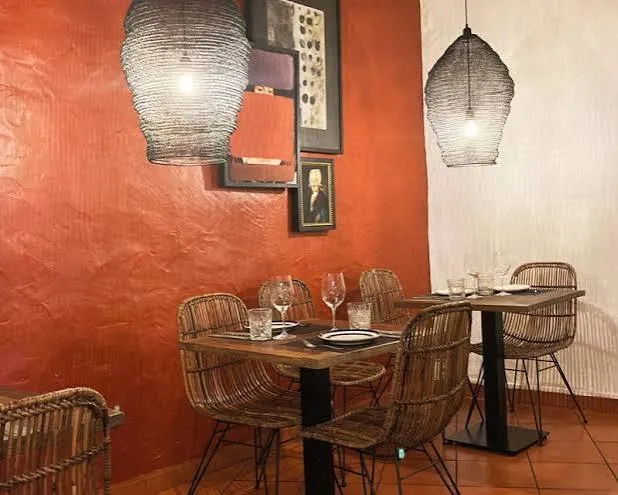 Terracotta-walled dining area at Larau with wicker chairs and pendant lamps