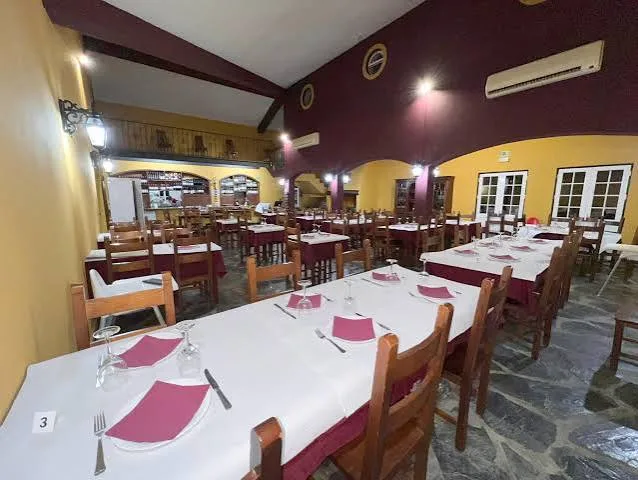 Dining room at O Broa with long white tables and magenta napkins