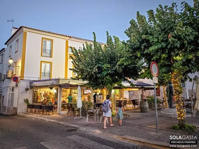 Restauração restaurant with a lit outdoor terrace under trees at dusk